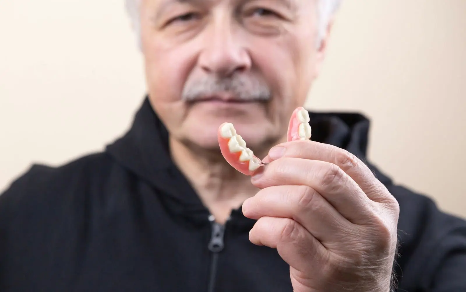 Older man holding a partial denture in his hand