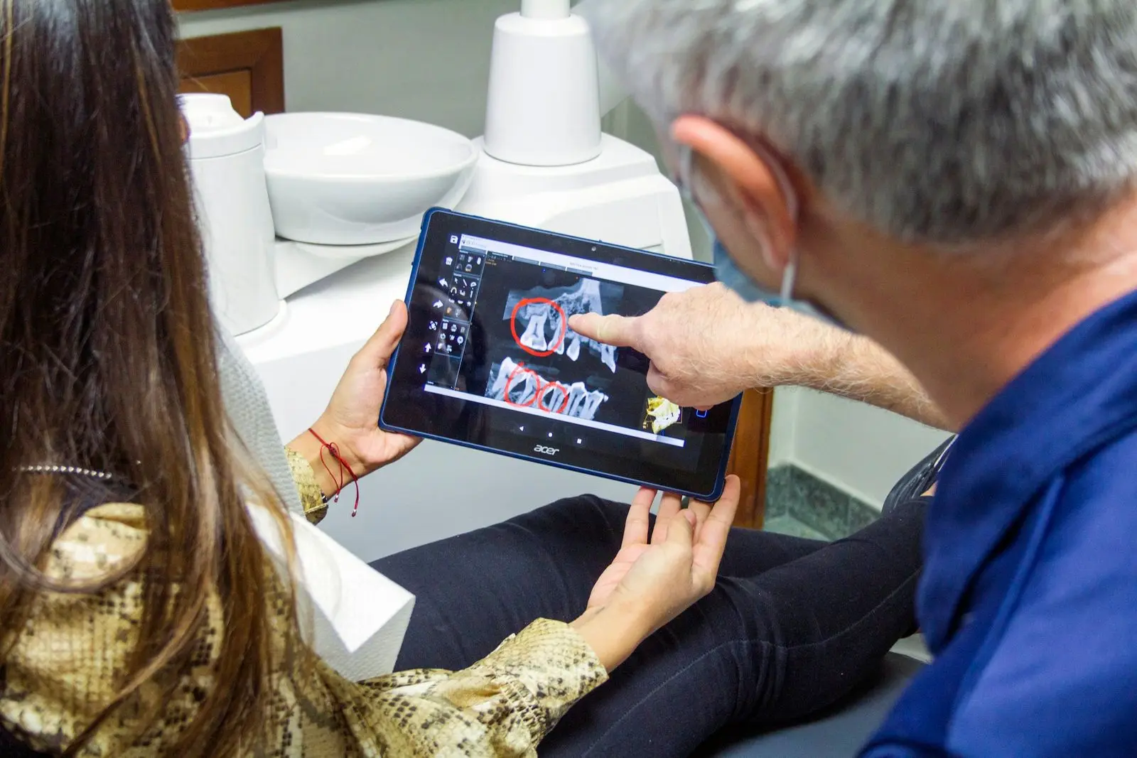 Dentist pointing to a scan on a tablet while explaining it to a patient